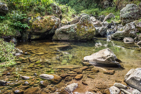 Natural nook with rocks in transparent stream with small  waterfall flowing