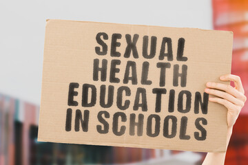 The phrase " Sexual Health Education in Schools " on a banner in men's hand with blurred background. Couple. Knowledge. Relationship. Love. Reproduction