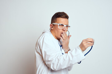 doctor in a medical gown with a stethoscope and glasses on a light background cropped view portrait