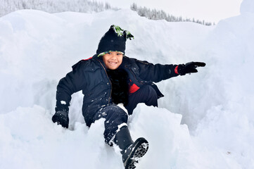 Fototapeta na wymiar Cute boy playing in the snow in winter.
