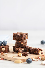 Selective focus to pieces of chocolate brownie with peanuts on a wooden board. Copy space.