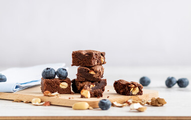 Selective focus to pieces of chocolate brownie with peanuts on a wooden board. Copy space.