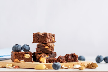 Selective focus to pieces of chocolate brownie with peanuts on a wooden board. Copy space.