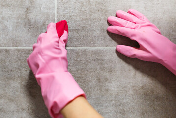 Woman hands in pink rubber gloves cleaning washing sink in bathroom. Close up. Disinfection of...