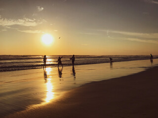 Ni&ntilde;os jugando en la playa al atardecer 