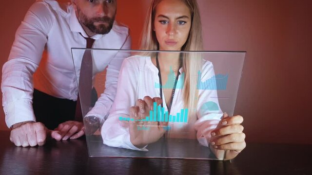 Futuristic Tablet in Business Office Man and Woman Colleagues Looking on Charts Animated on Glass. Static Full Frame With Motion Graphics