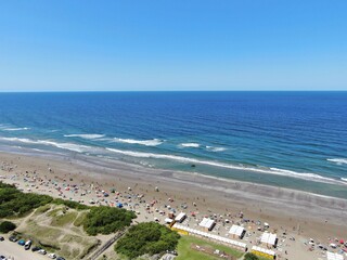 Vista a&eacute;rea de una zona de playa con gente en la playa y al fondo el mar azul , durante un d&iacute;a soleado de verano.
