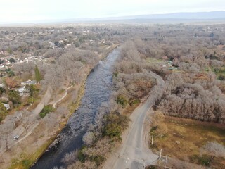 Vista a&eacute;rea de un r&iacute;o de monta&ntilde;a que atraviesa un valle, con rocas en el fondo del r&iacute;o, rodeado de &aacute;rboles.  