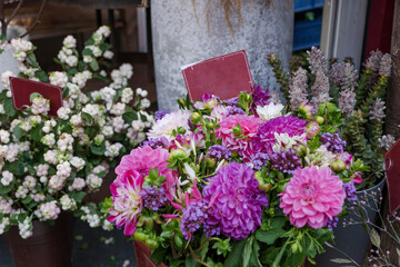 Selected focus view at purple, pink and white bouquet of blooming flowers in front of floral shop in outdoor market in Europe. Typical atmosphere of flower store.   