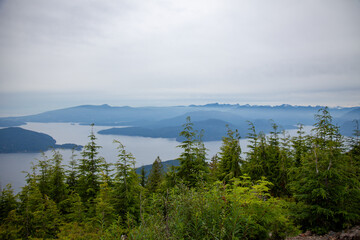 Fototapeta na wymiar Bowen Island lookout on a dreary, cloudy, foggy day from a view point on Cypress Mountain in British Columbia, Canada with the mountains, ocean and coastal islands in the backrgound