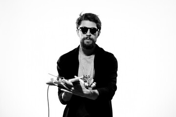 A man holds a guitar in his hands black leather jacket dark glasses music performance light background