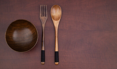 Wooden fork, spoon and bowl on wooden table with room for text