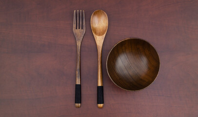 Wooden fork, spoon and bowl on wooden table