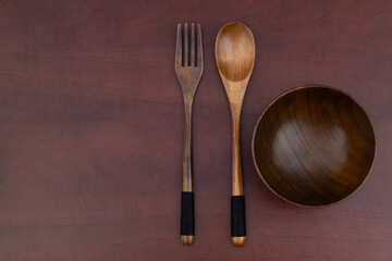 Wooden fork, spoon and bowl on wooden table with copy space