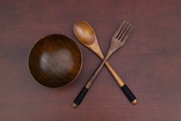 Wooden fork, spoon and bowl on wooden table