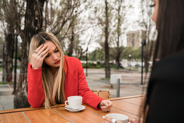 Two angry friends discussing while sitting at coffee shop.
