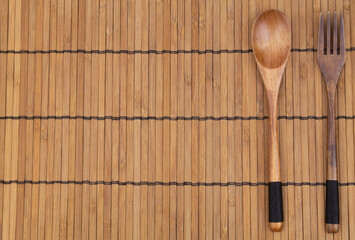 Wooden fork and  on bamboo place mat with copy space, top view 