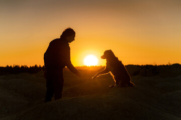 silhouette of a dog and a man at sunset. Relationship, communication, sunny. 