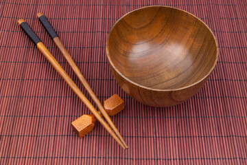 Wooden chopsticks and bowl on bamboo place mat