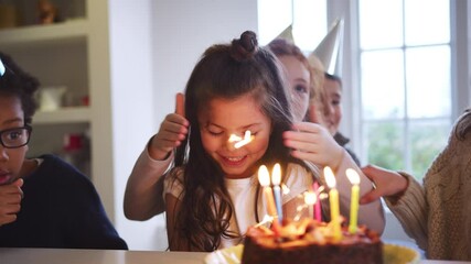 Young girl celebrating birthday with party and group of friends at home being given cake decorated with sparkler and candles - shot in slow motion - Powered by Adobe