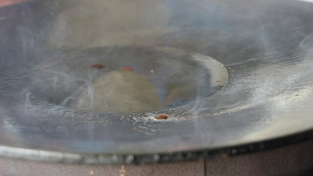 Street food vendor is pan-frying plain paratha roti, a kind of Indian flatbread, in smoking hot oil until crispy on the outside.