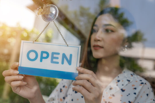 Woman Owner Turning Open Sign In Door Of Store