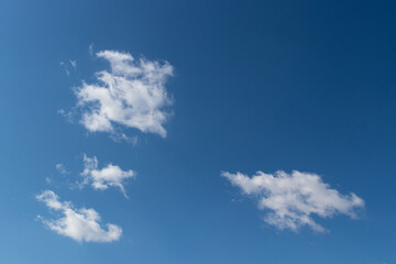 Dark blue sky with small fluffy clouds, background