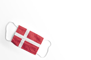 Fototapeta na wymiar Mascarilla con la bandera de Dinamarca impresa, sobre fondo blanco, aislado. 
