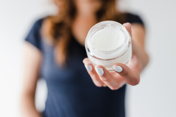 girl holding moisturizer jar in front of the camera showing the product, beauty bloggers and influencers reviews or tutorials