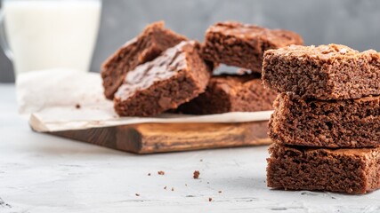 Brownie cookies lie on the board, in the background a glass with milk.