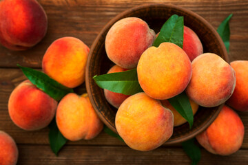 Ripe and tasty and juicy peaches lie on a plate on a wooden table. Large peaches on rustic wooden background, selective focus