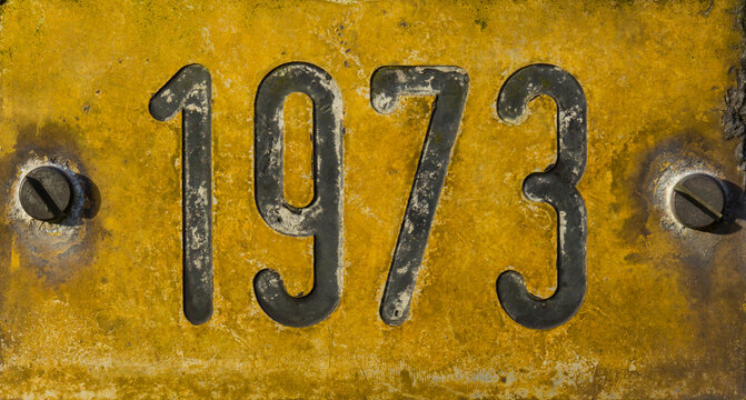 Gelbes verwittertes Schild mit Jahreszahl 1973
