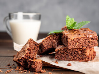 Brownie cookies lie on the board, in the background a glass with milk.