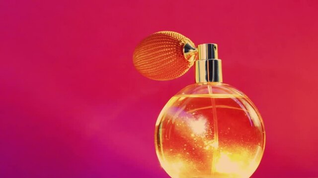 Golden fragrance bottle and shining light flares on pink background, glamorous perfume scent as holiday perfumery product for cosmetic and beauty brand, stock footage