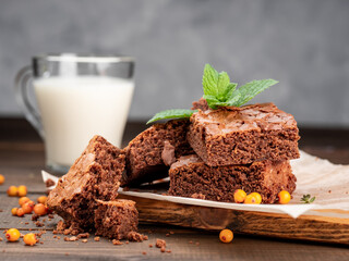 Brownie cookies lie on the board, in the background a glass with milk.