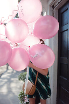 A teenage girl holding balloons walking down a city street