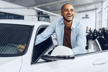 Portrait of a handsome happy African American man sitting in his newly bought car