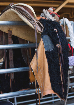 A pair of vintage wooly chaps hang from a bronc saddle