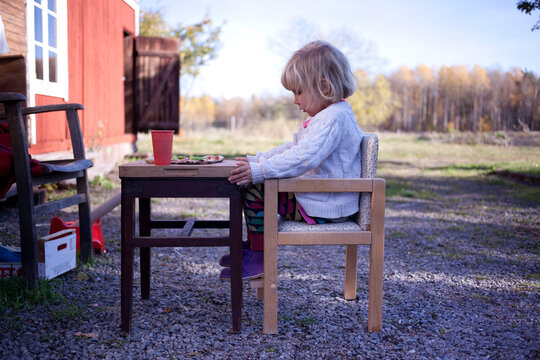 little girl having a small pizza for lunch outside.