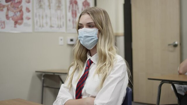 Secondary school students in UK wear masks in class as teen girl listens