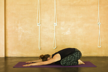 Woman doing child pose (BÔøΩlÔøΩsana) on yoga mat