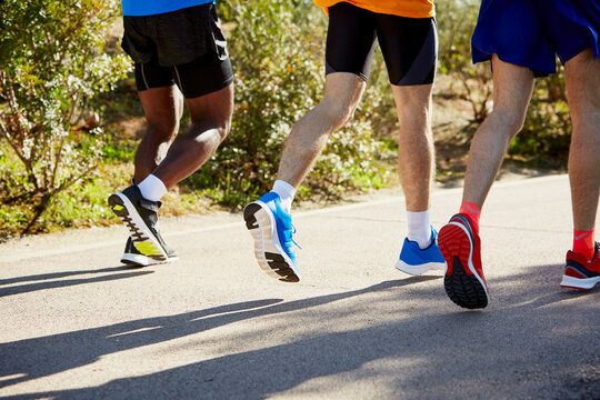 Low Section Of Male Athletes Running On Street