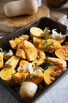 Butternut squash,smoked garlic and thyme in a roasting tin,ready to be cooked.