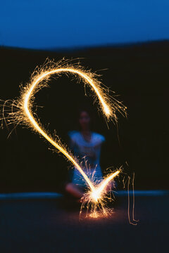 Anonymous woman drawing with sparkler in night