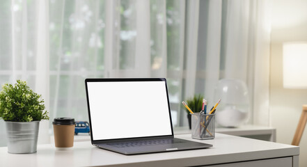 Laptop with blank screen on table in modern office. Mockup of advertisement.