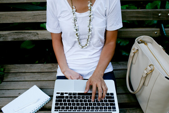 woman typing on keyboard on park bench