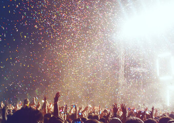 confetti falling and people raising hands at a concert