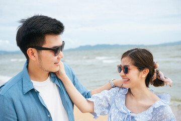 Romantic couple traveler wearing sunglasses touching each other cheeks on the beach.