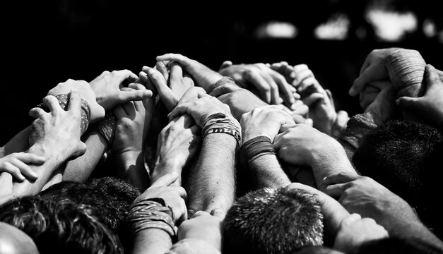 People touching each others arms above head in sunlight