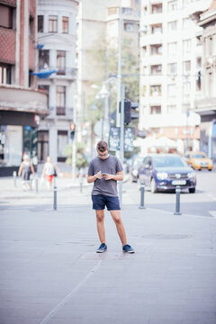 Teenager playing location-based augmented reality game on his smartphone in the city